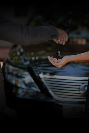 Vertical shot of a car dealer passing the key to the owner